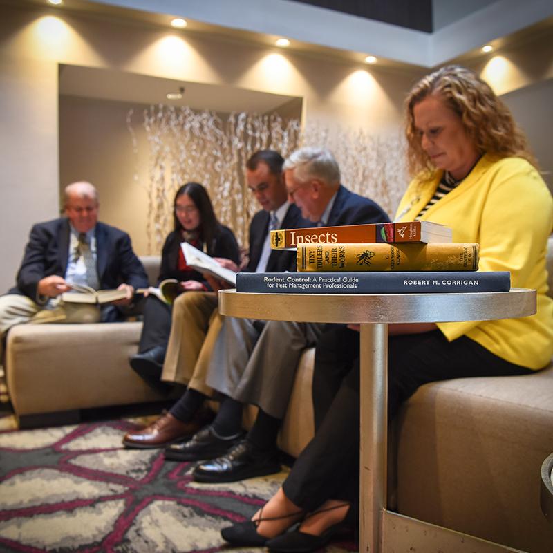 Focused group of professionals reading pest management books in a lounge area."