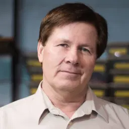 headshot of Middle aged man with brown hair and a blurry background.