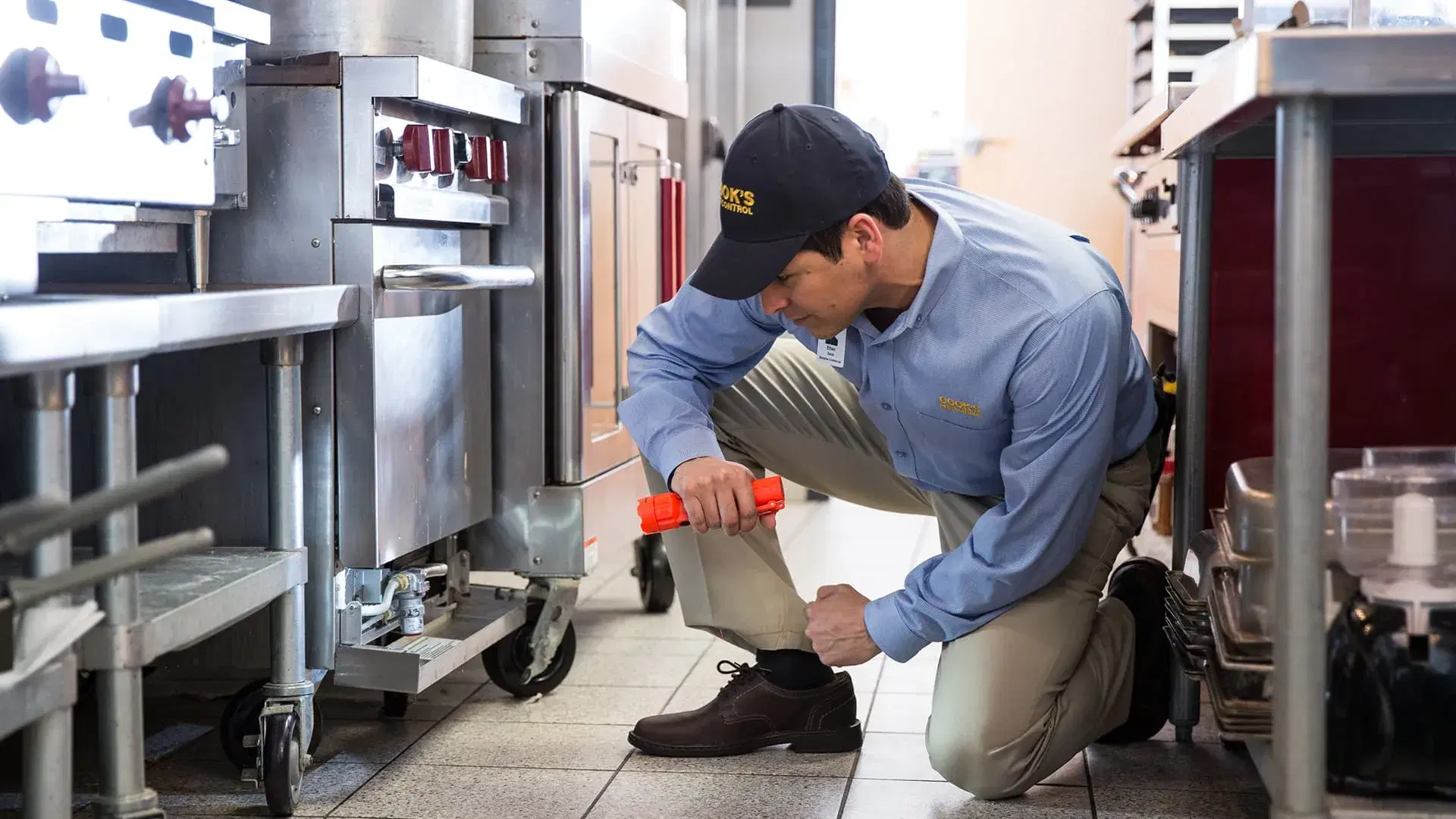 man holding flashlight on kitchen floor looking for termites