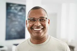 headshot of Happy man with glasses in a beige shirt indoors.