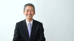 headshot of Smiling man in a suit with striped tie against a white background.